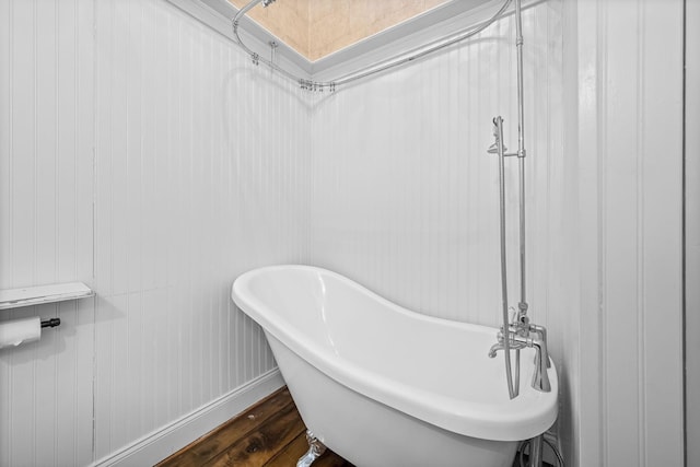 full bathroom with baseboards, a freestanding bath, and wood finished floors