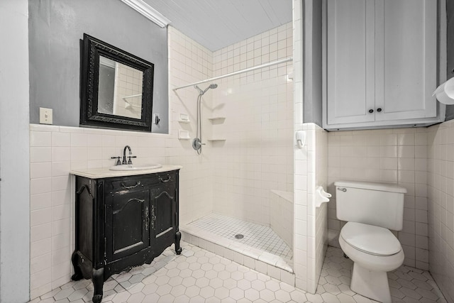 full bathroom featuring toilet, vanity, tile walls, tile patterned floors, and a stall shower