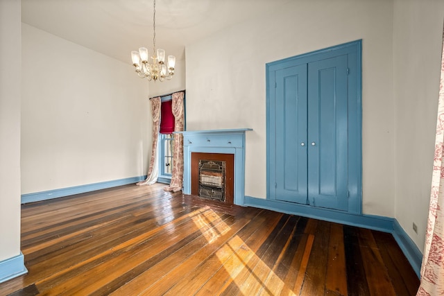 unfurnished living room featuring a chandelier, baseboards, and hardwood / wood-style flooring