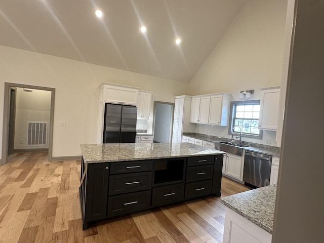 kitchen with dark cabinets, a center island, a sink, visible vents, and appliances with stainless steel finishes