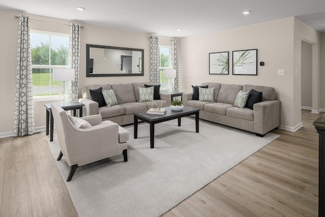 living area featuring a wealth of natural light, baseboards, and light wood finished floors