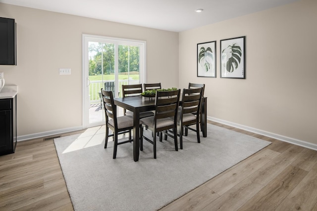 dining space with visible vents, light wood-style floors, and baseboards