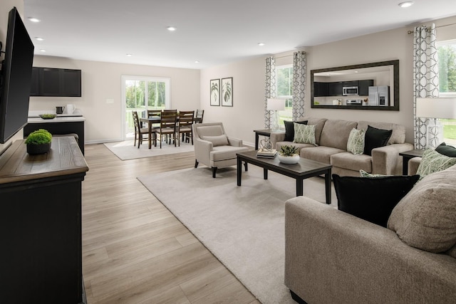 living area featuring recessed lighting, baseboards, and light wood-style floors