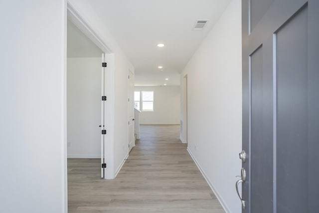 hall featuring light wood-type flooring, baseboards, visible vents, and recessed lighting