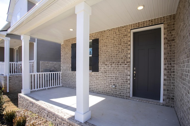 property entrance featuring a porch and brick siding