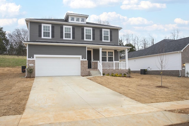 american foursquare style home with central air condition unit, driveway, covered porch, a garage, and brick siding