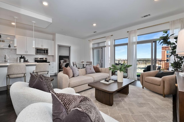 living room with light wood-type flooring, visible vents, and recessed lighting