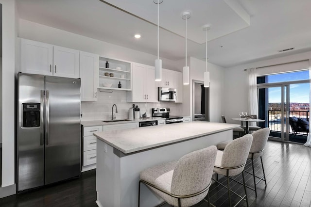 kitchen with a sink, stainless steel appliances, white cabinetry, open shelves, and backsplash