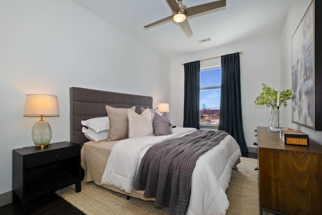 bedroom featuring a ceiling fan, visible vents, and wood finished floors