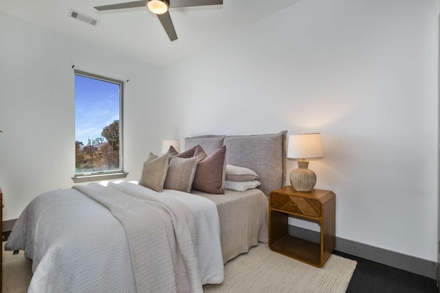 bedroom with ceiling fan, wood finished floors, visible vents, and baseboards