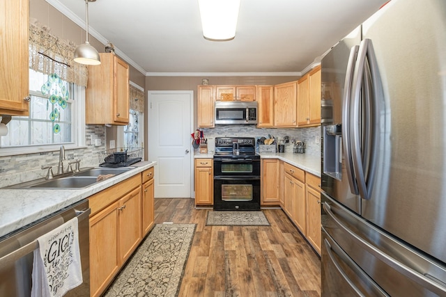 kitchen with stainless steel appliances, wood finished floors, a sink, and ornamental molding