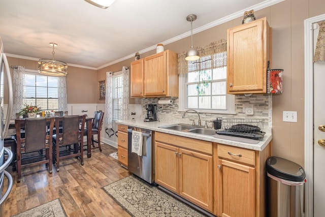 kitchen with wood finished floors, light countertops, stainless steel dishwasher, and a sink