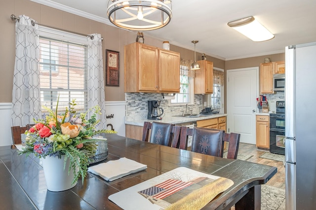 dining area with light wood-style flooring and ornamental molding