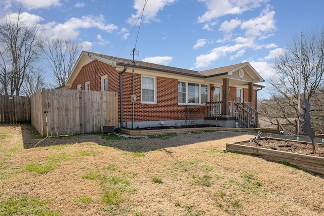 exterior space featuring a yard, fence, and brick siding