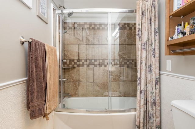 bathroom featuring enclosed tub / shower combo, wainscoting, and toilet