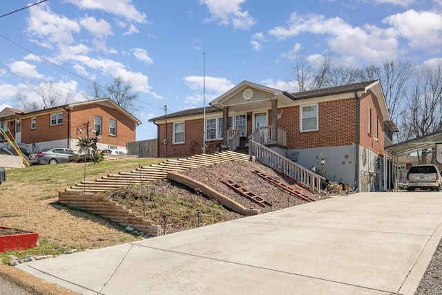 ranch-style house featuring covered porch, concrete driveway, brick siding, and stairs