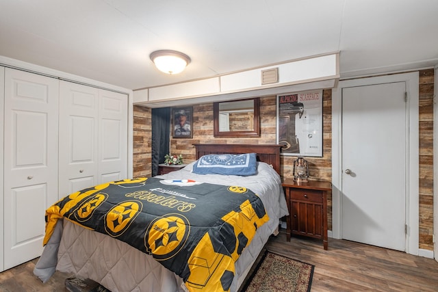 bedroom featuring a closet, wood walls, and wood finished floors