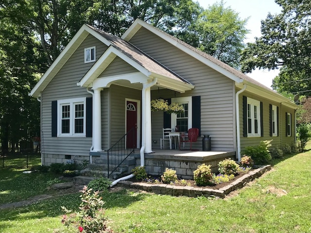 view of front facade featuring a porch, a front yard, and a shingled roof