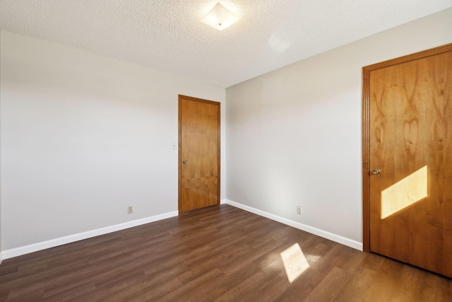 unfurnished bedroom featuring dark wood finished floors, a textured ceiling, and baseboards