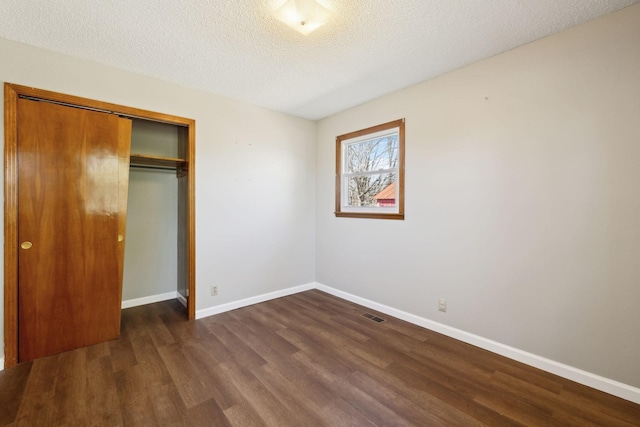 unfurnished bedroom with visible vents, a textured ceiling, baseboards, and wood finished floors