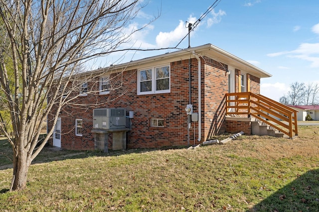 view of property exterior featuring cooling unit, brick siding, and a yard