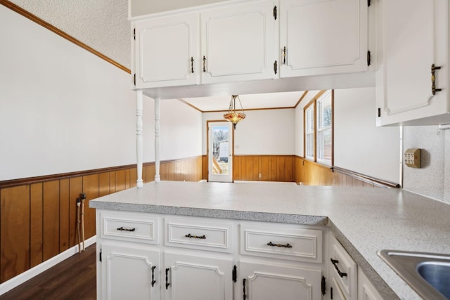 kitchen with a wainscoted wall, white cabinetry, and wooden walls