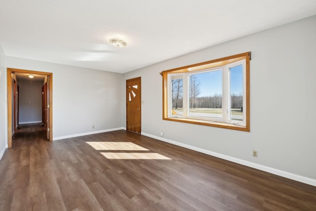 unfurnished room featuring dark wood-style floors, a textured ceiling, and baseboards