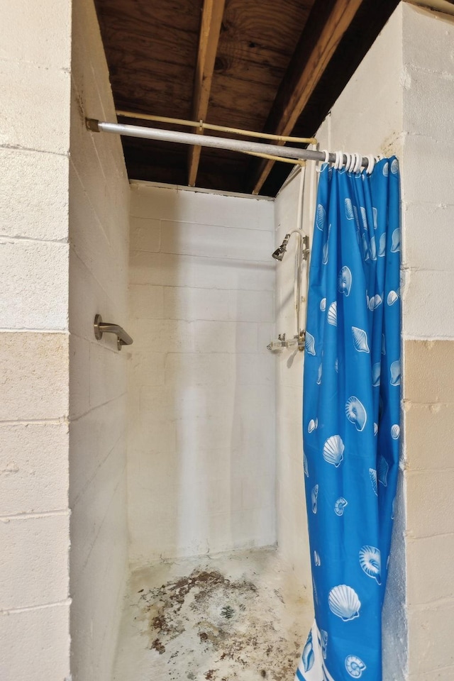 bathroom featuring concrete flooring, concrete block wall, and a shower with shower curtain