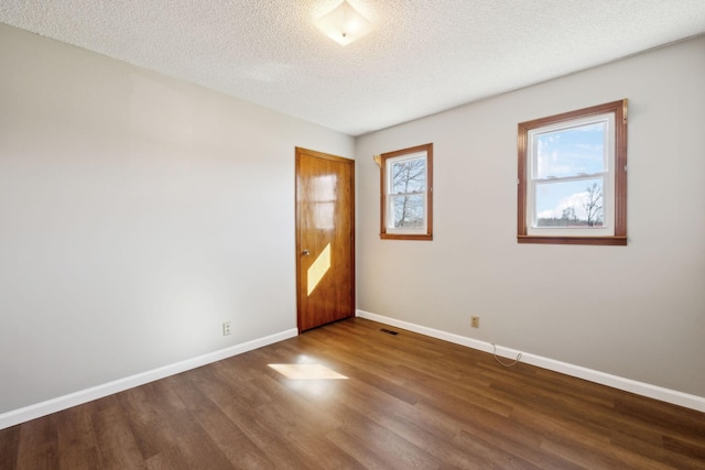 unfurnished room with visible vents, a textured ceiling, baseboards, and wood finished floors