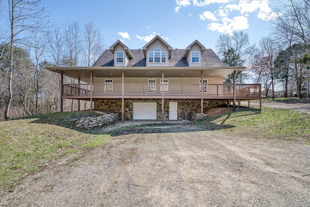 view of front facade with stone siding, driveway, a deck, and an attached garage