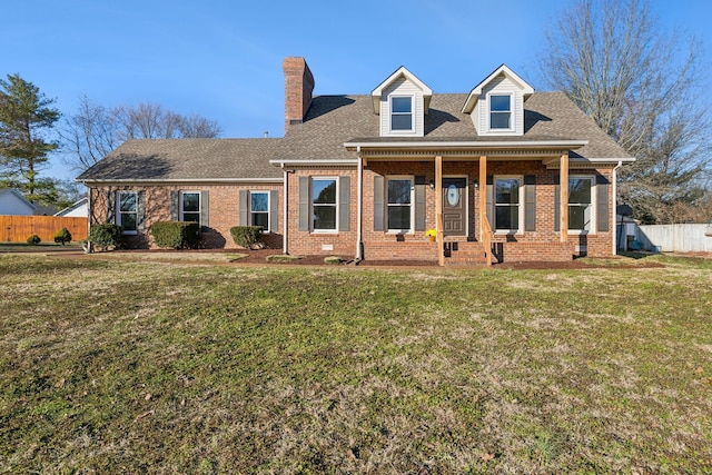 cape cod house featuring brick siding, a front yard, fence, and a shingled roof