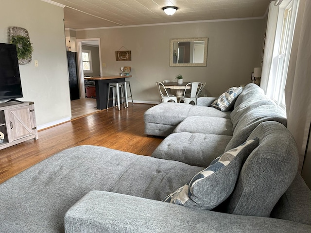 living room with crown molding, baseboards, and wood finished floors