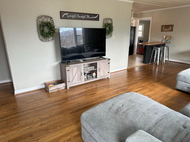 living room with baseboards, ornamental molding, and wood finished floors