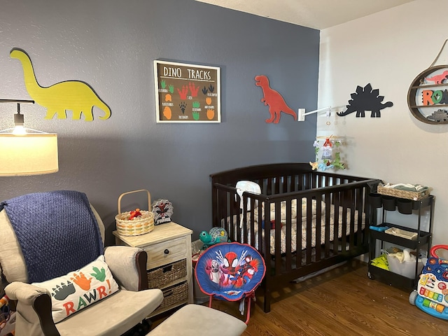 bedroom featuring a crib and wood finished floors