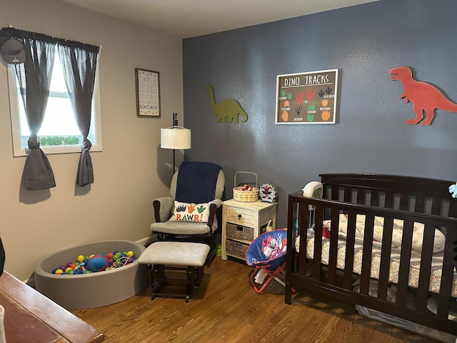 bedroom featuring a crib and wood finished floors