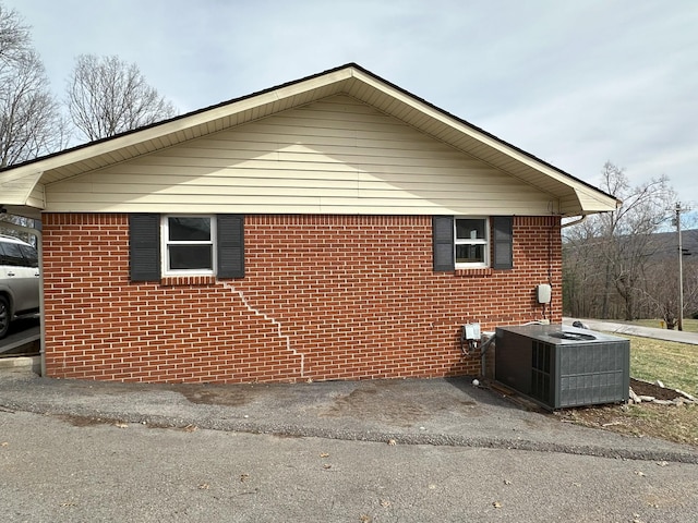 view of side of home featuring central AC and brick siding