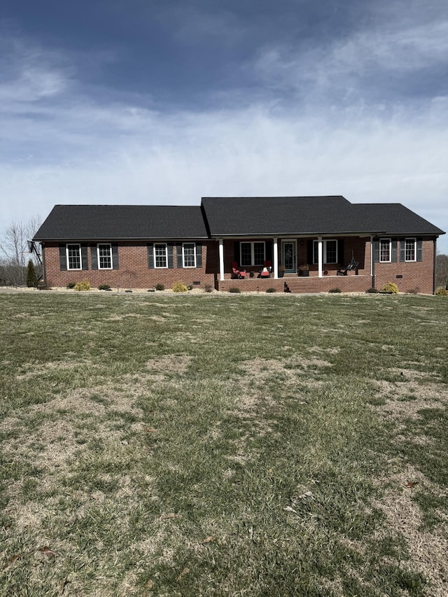 ranch-style home with crawl space, brick siding, covered porch, and a front yard