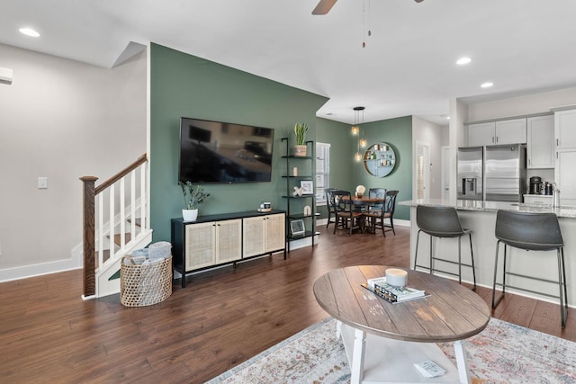 living room with dark wood-style floors, ceiling fan, stairs, and baseboards