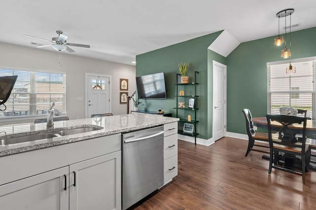 kitchen featuring light stone counters, dark wood-type flooring, decorative light fixtures, stainless steel dishwasher, and a sink