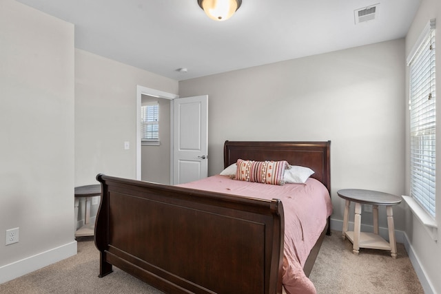 bedroom with visible vents, light carpet, baseboards, and multiple windows