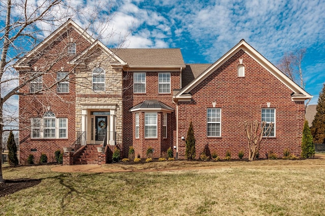 view of front facade with stone siding, a front lawn, and brick siding