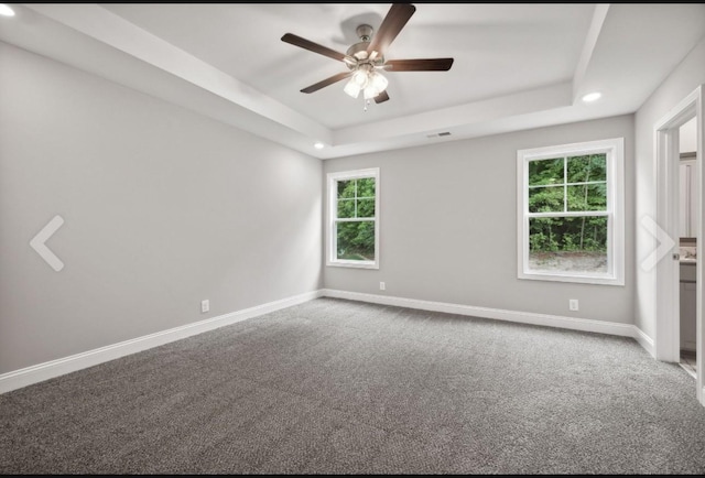 empty room featuring carpet floors, baseboards, a tray ceiling, and a ceiling fan