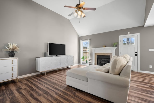 living area with a fireplace, dark wood-type flooring, ceiling fan, high vaulted ceiling, and baseboards