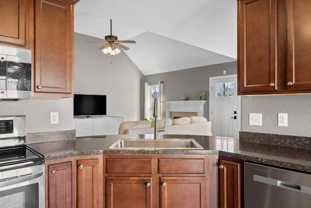 kitchen with ceiling fan, appliances with stainless steel finishes, open floor plan, vaulted ceiling, and a sink