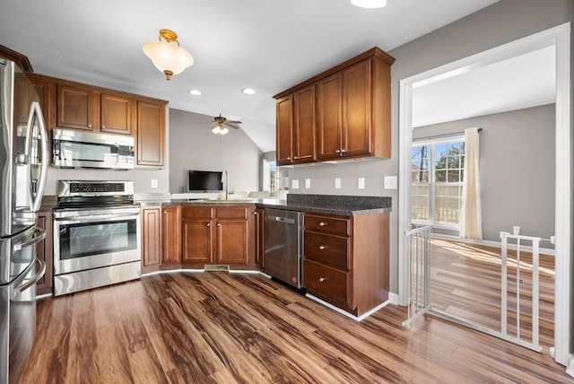 kitchen featuring appliances with stainless steel finishes, brown cabinetry, and dark wood-type flooring