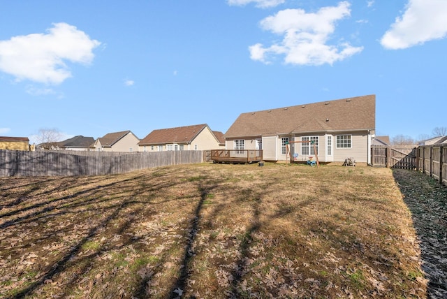 back of house featuring a fenced backyard, a lawn, and a deck