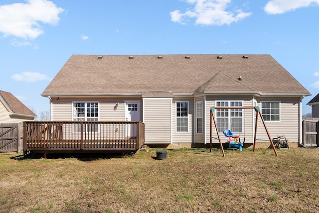 rear view of house with a wooden deck, fence, roof with shingles, and a yard