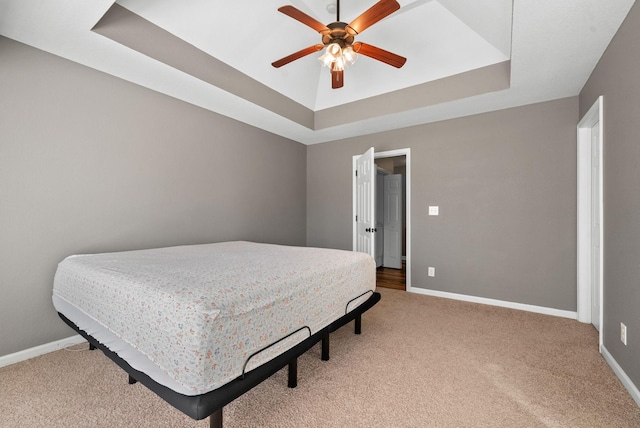 bedroom with light carpet, baseboards, and a raised ceiling