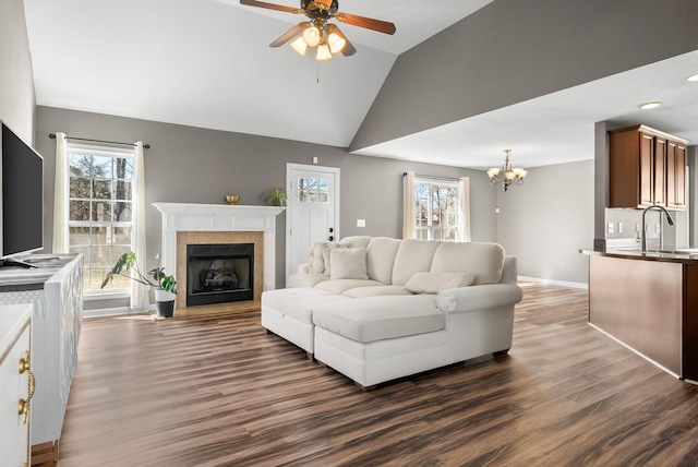 living room with ceiling fan with notable chandelier, dark wood-style flooring, plenty of natural light, and a fireplace