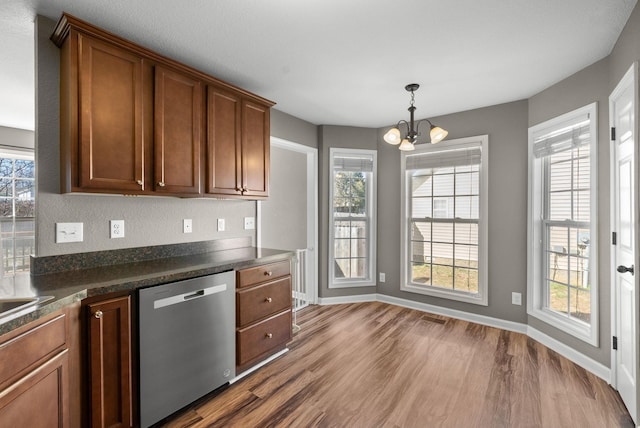 kitchen with dark wood finished floors, dark countertops, brown cabinets, an inviting chandelier, and stainless steel dishwasher